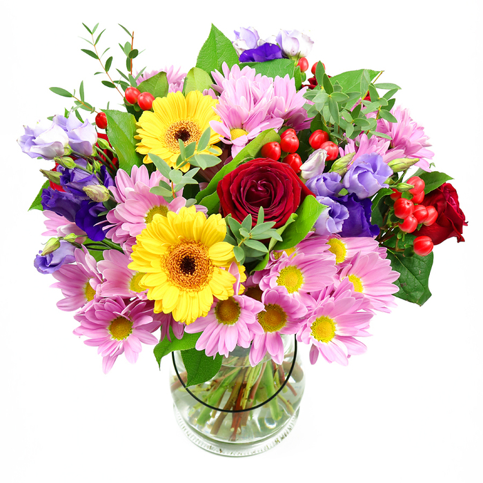 In this image, a luxurious mixed bouquet rises proudly from a simple clear glass vase, the white background making its many colours and forms appear especially vivid. At its centre, deep red roses unfurl in tight, velvety spirals, their classic shape and rich tone giving the arrangement a timeless, romantic anchor. Radiant yellow gerbera daisies with dark brown-orange centres sit among them like small suns, bringing a joyful brightness reminiscent of weekend markets around Sutton and Carshalton. Surrounding these stars are generous clusters of soft pink daisies or chrysanthemums, each bloom composed of delicate, slender petals that fan out from a small yellow core, creating a cushion of gentle pastels that softens the bolder shades. Threading through the composition are slender stems of lisianthus in purple and lavender, their graceful, bell-shaped flowers opening at different stages, from tight buds to fully unfurled blooms, adding depth and a soothing, cool-toned refinement. Intermittent pops of shiny red hypericum berries add a berry-like roundness and contemporary texture, echoing the rich red of the roses while giving the eye new shapes to explore. A variety of green foliage frames and supports the flowers-broad, deep-green leaves mingle with finer, brighter sprigs, recalling the layered greenery you might see in Sutton's parks after rain. The transparent vase reveals the neatly trimmed stems and clear water, emphasizing the craftsmanship behind the arrangement and how freshly it has been put together, as though ready for same-day delivery to a home near Sutton station or a café close to Trinity Square. The overall mood is uplifting, generous, and warmly celebratory, suitable for birthdays, anniversaries, or simply to bring a burst of garden-like colour indoors.